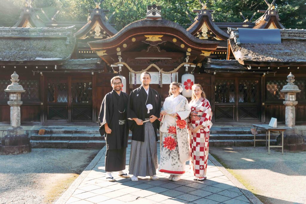 Bride and groom standing in front of the main hall of a Kyoto shrine during a traditional Shinto ceremony
