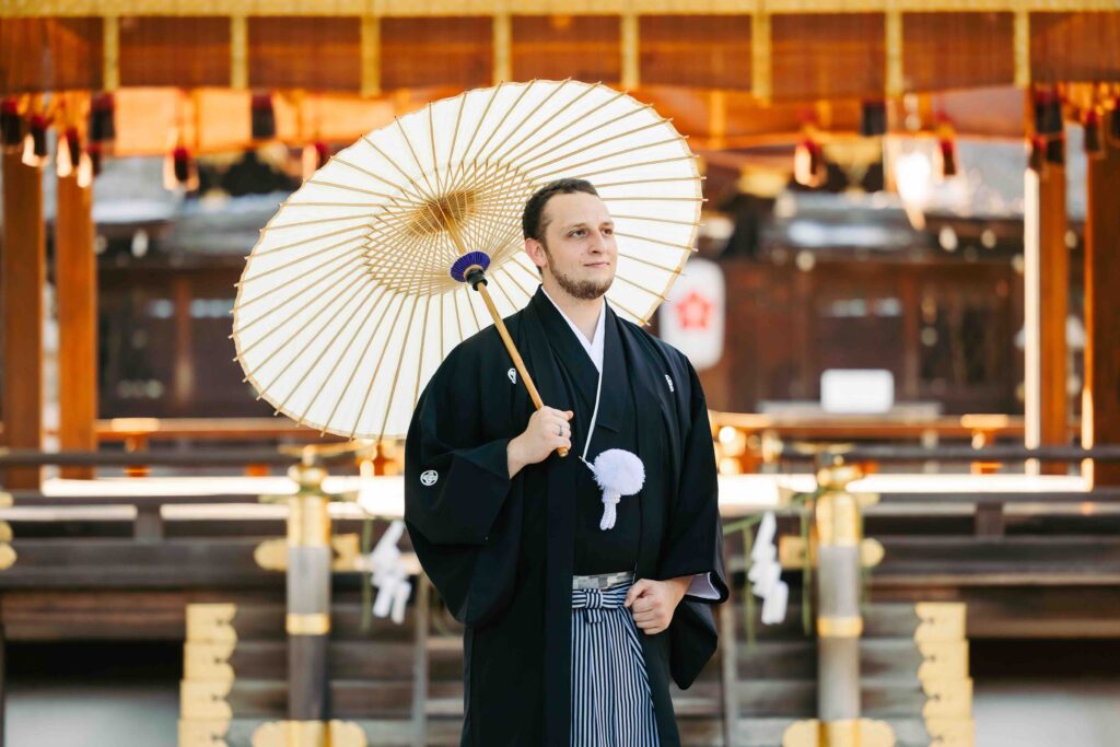 Elegant portrait of the groom in the serene grounds of a Kyoto shrine during their intimate autumn wedding
